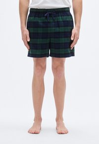 Καρό σορτς σε πράσινο, ναυτικό και μαύρο χρώμα. Απαλό ύφασμα με ελαστική μέση και κορδόνι. Μήκος μέχρι το γόνατο. Χωρίς μοτίβα ή διακοσμητικά.