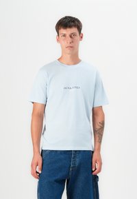 Light blue cotton t-shirt with short sleeves and round neckline. Centered printed logo "JACK & JONES" in a darker color.
