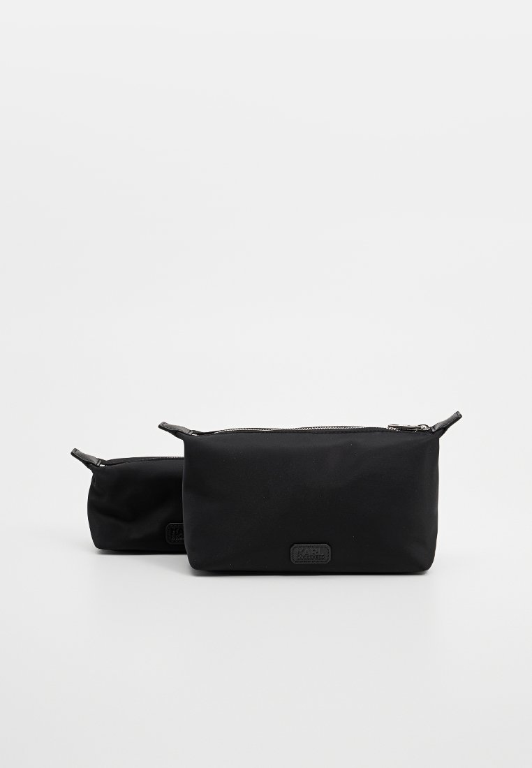 Zwei schwarze Kosmetiktaschen aus glattem Stoff mit Reißverschluss. Eine Tasche ist größer als die andere, beide verfügen über ein dezentes Logo.