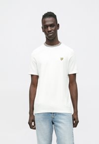 Bela majica s kratkimi rokavi in sivim ovratnikom ter majhnim rumenim vezenim logotipom na levi strani prsi. Iz bombaža, sproščen kroj.