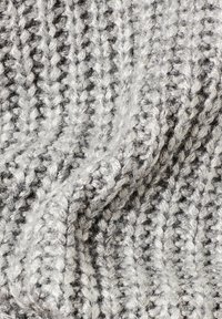 Plaid en tricot dans des nuances de gris et blanc. Présente un motif texturé avec des points apparents, des fibres douces et une apparence confortable.