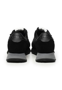 Scarpe sportive nere con tomaia in camoscio e pelle, suola in gomma grigia e logo in rilievo sul tallone. Presentano un colletto e una linguetta imbottiti.