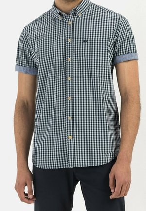 Korte mouwen overhemd met een zwart-wit gingham patroon en lichtblauwe denim accenten op de mouwen. Bevat een borstzak en houten knopen.