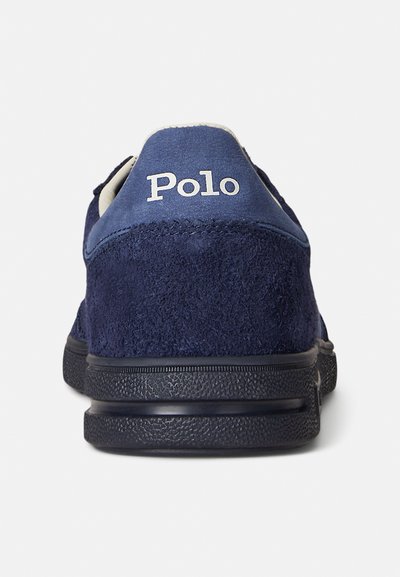 Sapatilha em camurça azul-marinho com contraforte em couro azul, apresentando o logótipo branco "Polo" na parte de trás e sola de borracha preta texturada.