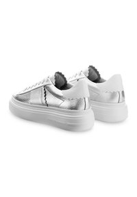 Silberne Leder-Plateausneaker mit strukturierter Oberfläche, weißer Gummisohle und gewellten schwarzen Akzenten an Zunge und Ferse.