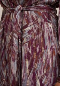 Purple and grey patterned fabric with golden accents, featuring a tie belt at the waist. Texture appears soft with brushstroke designs.