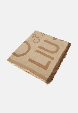 Foulard carré beige et marron avec de grandes lettres en bloc et des bords à franges, plié à plat sur un fond clair.