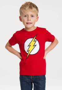 Red cotton t-shirt featuring a large white circle with a yellow lightning bolt graphic. Styled with short sleeves and a crew neckline.