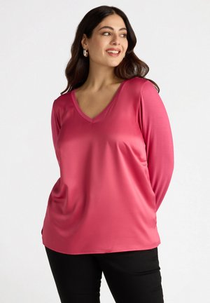 Top de manga larga rosa con escote en V, hecho de una tela suave. Presenta un corte relajado, con suaves caídas y un diseño de color sólido.