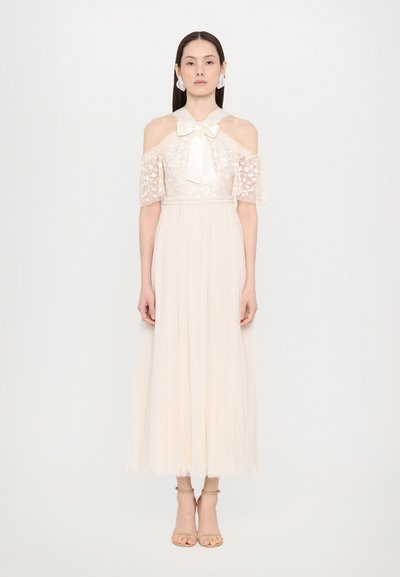 Beige off-shoulder kjole med blonde detaljer, korte puffærmer og en silkebow ved halsudskæringen. Flydende, plisseret nederdel med prikker.