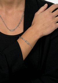 Silver chain necklace with rectangular links, paired with a matching bracelet. Both pieces have a polished finish and minimalist design.