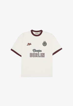 Witte T-shirt met korte mouwen en bordeauxrode afwerking, "Escape BERLIN" tekst op de voorkant in het midden, "Mitte" op de linkerborst en een cirkelvormig embleem met twee sterren op de rechterborst.