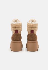 Bottines beige avec un col pelucheux. Fabriquées en cuir et en daim, avec une semelle en caoutchouc et une accent maroon sur le talon. Fini texturé.