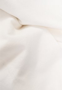 Tessuto bianco con una superficie liscia, leggermente stropicciato, che mostra un materiale morbido e leggero. Nessun motivo o decorazione visibile.