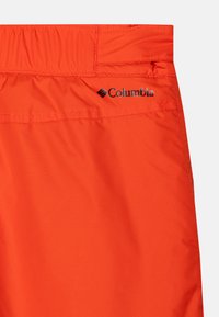 Orange athletic shorts with a textured fabric and an elastic waistband. Features the Columbia logo in black on the back.