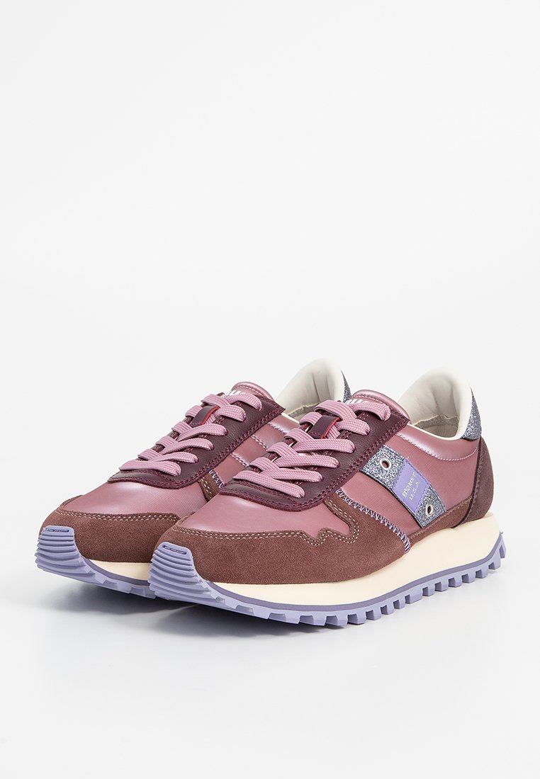 Un paio di sneaker basse viola e marroni con lacci rosa, suola testurizzata e striscia laterale metallica, esposte su uno sfondo bianco.