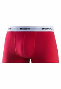 Red boxer briefs with a fitted design, made from soft fabric. Features a white waistband with black "Bench." logo and contrasting seams.