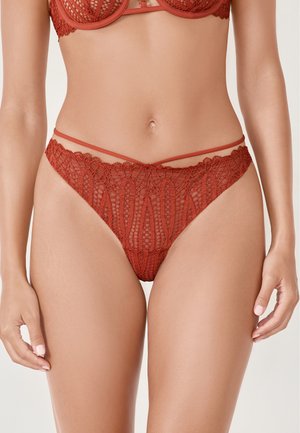 String en dentelle rouge profond orné de motifs floraux complexes, avec de fines bretelles sur les côtés et une taille festonnée pour une finition délicate.