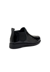 Botines de cuero negro con paneles laterales elásticos, punta redonda, textura suave y un bajo tacón de goma.
