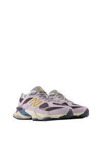 Zapatillas deportivas moradas y grises con parte superior de malla y gamuza, acentos amarillos, suela resistente y cuello acolchado para mayor comodidad.