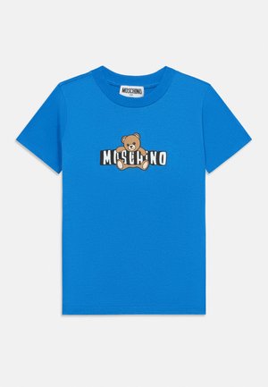 T-shirt enfant bleu à manches courtes avec un motif d'ourson en train d’enlacer le texte noir et blanc "MOSCHINO" sur le devant.