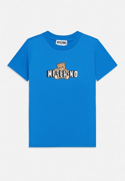 T-shirt enfant bleu à manches courtes avec un motif d'ourson en train d’enlacer le texte noir et blanc "MOSCHINO" sur le devant.