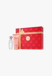 Set de regalo de Estee Lauder que incluye un frasco de perfume de vidrio transparente con tapa plateada y loción corporal rosa, empaquetado en una caja roja con puntos dorados y cinta.