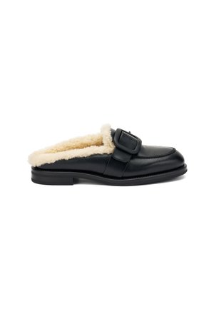 Mule in pelle nera con foderatura morbida color crema, dotata di una grande fibbia nera e una suola bassa e piatta per un facile indossamento.