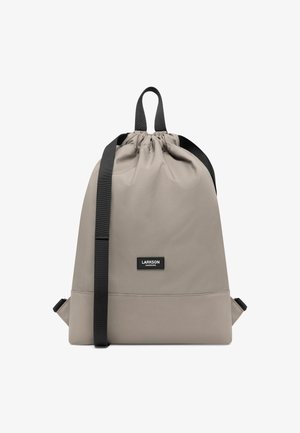 Ljusgrå dragkedjeryggsäck tillverkad av slitstarkt tyg, med svarta remmar och en logotypapplikation. Slät textur med en minimalistisk design.