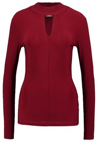 Långärmad bordeauxfärgad topp med hög krage och en nyckelhålsöppning vid halsen, tillverkad av smidigt, stretchigt tyg.