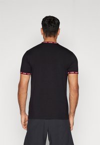 Black short-sleeve t-shirt featuring a red and white logo band at the neckline and sleeves. Fabric appears smooth with a fitted design.