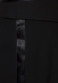 Jupe noire en tissu lisse avec un accent satiné le long du centre, créant un contraste de texture et de brillance.