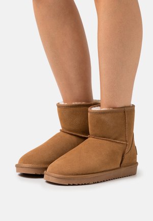 Brązowe zamszowe trzewiki z miękką, futrzaną podszewką, okrągłym noskiem i przeszyciami. Płaska gumowa podeszwa z teksturowanym gripem.