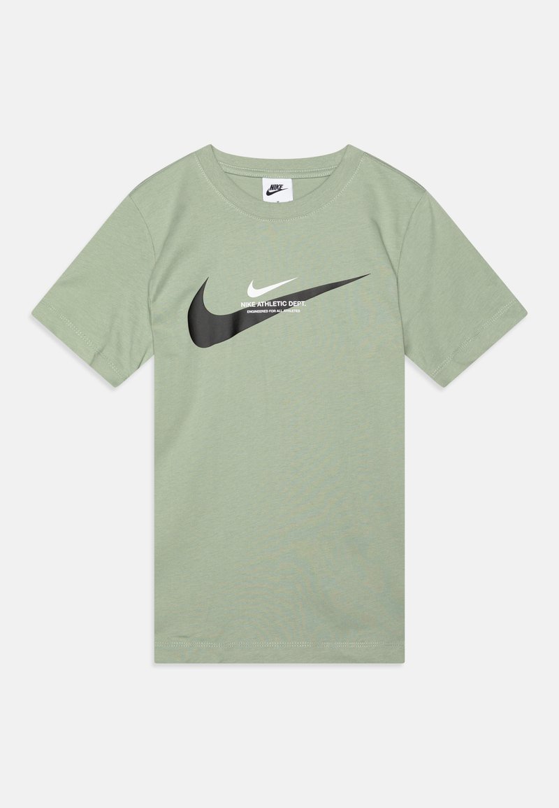 Vihreä puuvillainen t-paita, jossa on lyhyet hihat, pyöreä kaula-aukko ja suuri musta Nike-logo valkoisella lisätekstillä.
