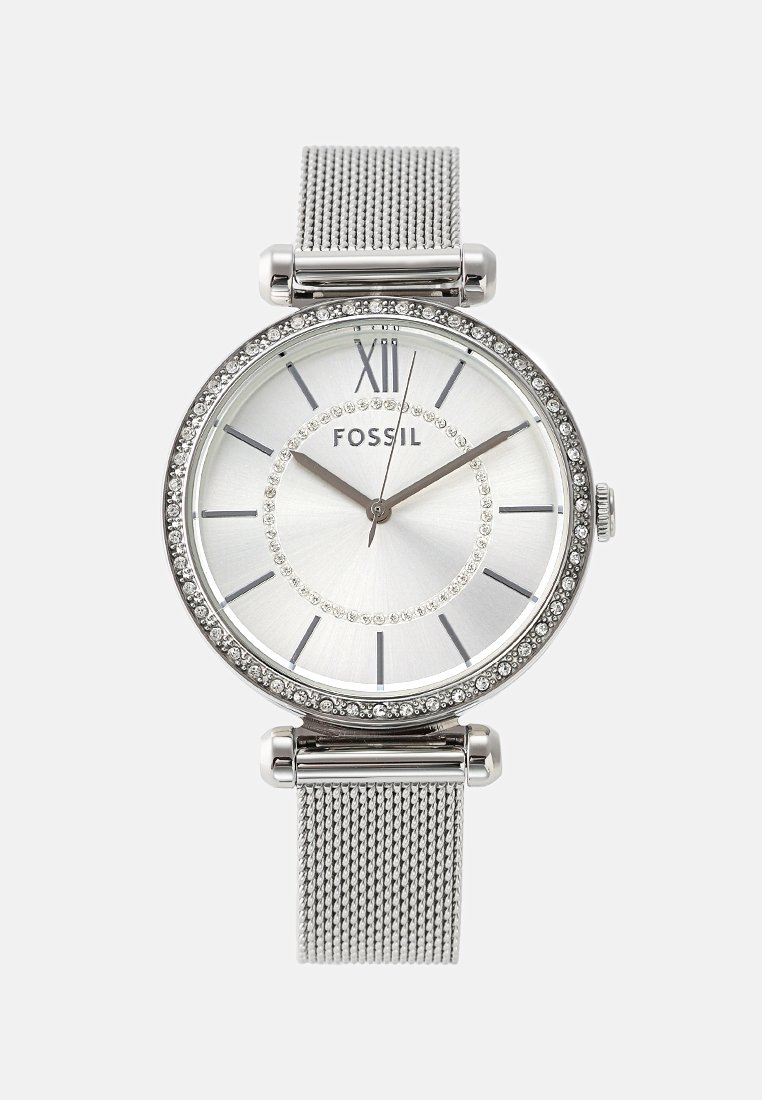 Reloj metálico plateado con una caja redonda, acentos de cristal, una esfera blanca, marcadores de hora plateados y una correa de malla. Presenta el nombre de la marca "FOSSIL."