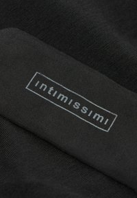 Černá tkanina s hladkým povrchem, na níž je bílá nálepka s nápisem "intimissimi" v obdélníkovém rámečku.