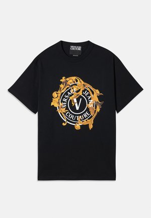 Czarny bawełniany t-shirt z okrągłym złotym i białym logo z ozdobnym wzorem, na którym widnieje napis "Versace Jeans Couture" oraz centralne V.