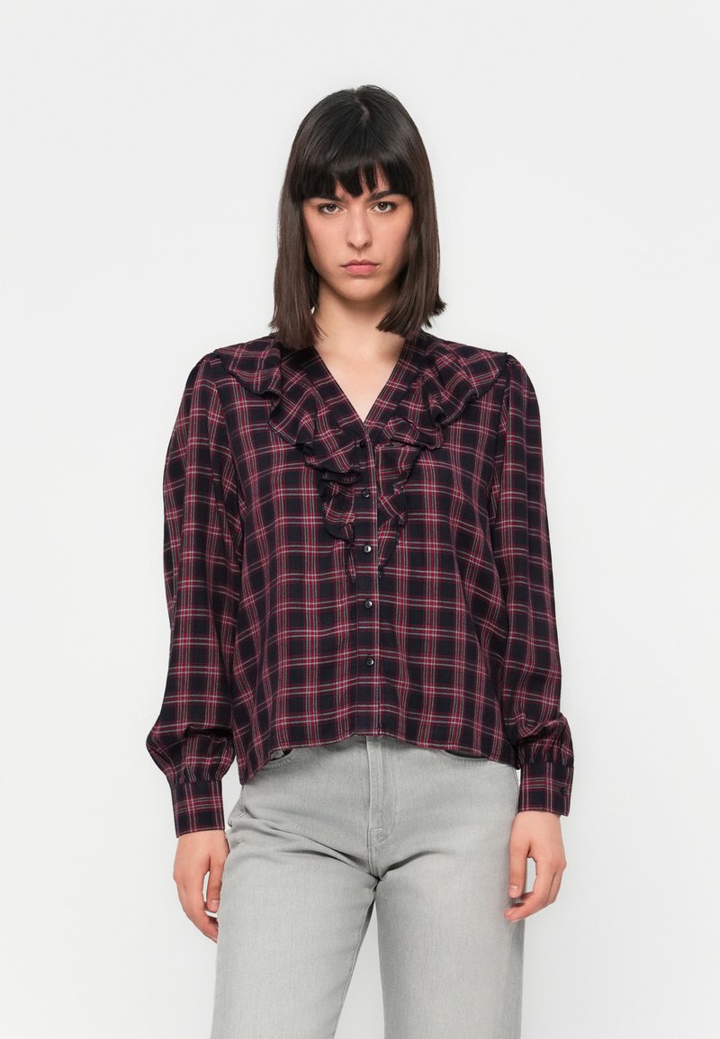 Dark plaid blouse with ruffled neckline and front buttons. Features long sleeves with gathered cuffs. Main colors: navy, red, and white.