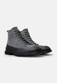 Botas gris con cordones, con un upper de cuero liso y suela de goma negra con textura estriada. Diseño de caña alta con puntera reforzada.