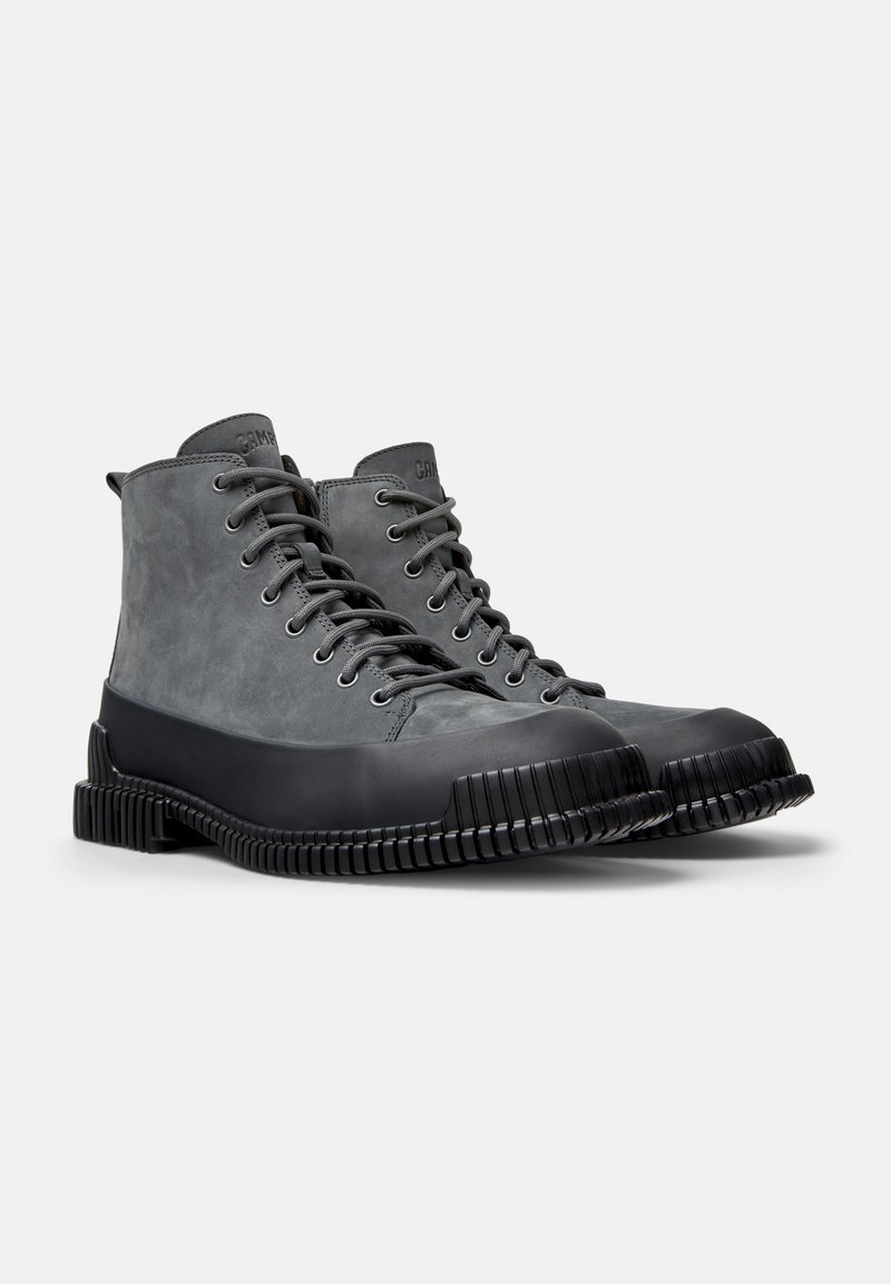 Gray lace-up boots with a smooth leather upper and black rubber sole featuring a ridged texture. High-top design with reinforced toe.