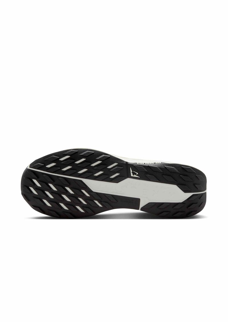 Suela de zapato con una superficie de goma negra que presenta patrones de tracción multidireccional y un área central de acento blanca para un agarre estable.