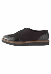 Crne suede cipele na vezanje s sjajnim crnim kapicom i brogue detaljima, s debelim gumeni potplat i tamnom akcentom na srednjem potplatu.