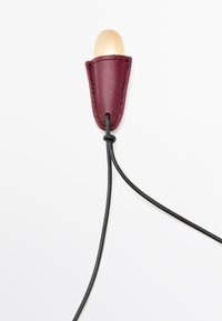 Portacavi in cuoio color bordeaux con una punta in legno liscia e arrotondata. Un cavo nero emerge dal centro, caratterizzato da dettagli di cucitura minimi.