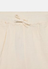 Ljusbeige bomullsshorts med en gathered midja, försedd med en dragsko och subtil textur med veck längs midjan.