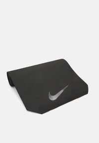 Esterilla de yoga negra con una superficie texturizada, que presenta un logotipo de Nike en blanco. La esterilla está enrollada en parte con un borde suave.