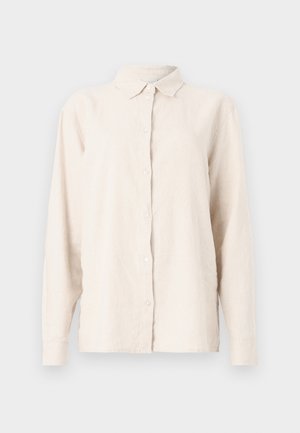 Lys beige lin skjorte med knappelukking foran, spiss krage og lange ermer. Stoffet har en teksturert, noe rynket utseende.