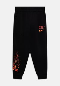 Černé sportovní kalhoty s elastickým pasem, červené a oranžové logo CR7 a Nike na stehně, a oranžový geometrický křížový vzor na dolní části nohy.