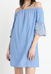 Blue off-shoulder dress with embroidered bell sleeves. Made from lightweight fabric, featuring floral patterns on sleeve hems. Simple, A-line design.