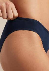 Navyblauwe katoenen ondergoed met een gladde textuur en verfijnde kantafwerking langs de tailleband, met een snug fit en een klassiek ontwerp.