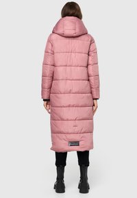 Long padded coat in soft pink, featuring a hood, vertical quilted design, and black label detail at the hem. Waterproof fabric with a smooth texture.